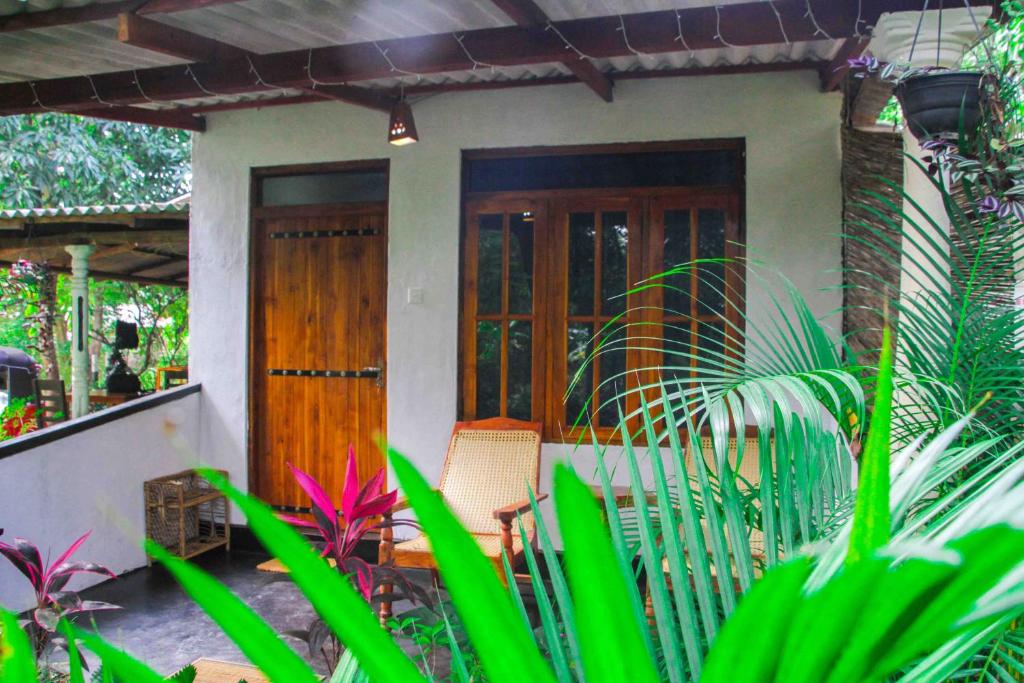 ein kleines Haus mit Holztüren und Pflanzen in der Unterkunft Manju Homestay in Sigiriya