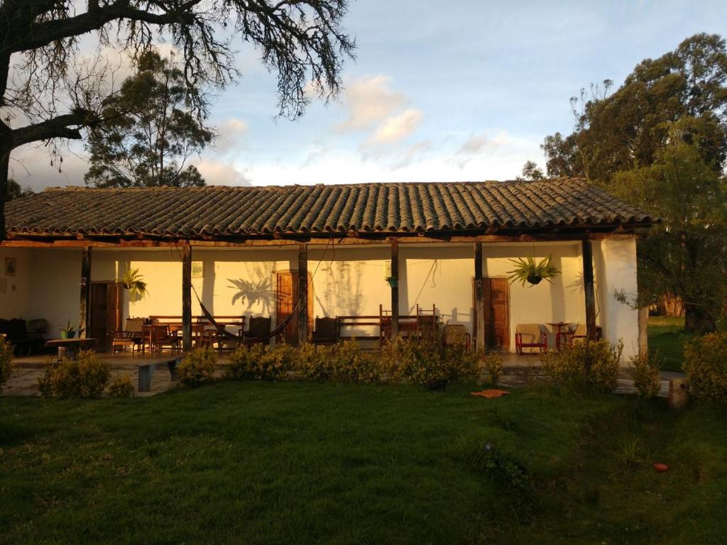 een paviljoen met tafels en stoelen in een tuin bij Posada Turistica Altamisal in Firavitoba