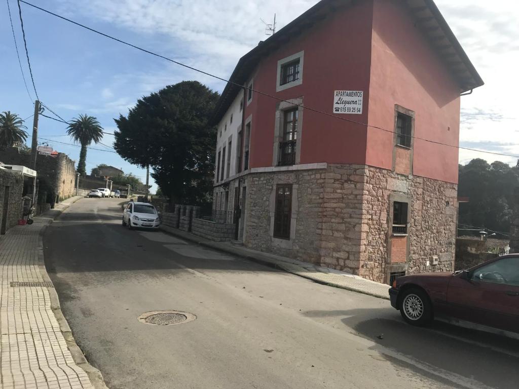 un edificio rojo al lado de una calle en Apartamentos Rurales LLeguera en Llanes