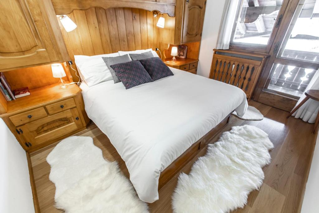 una camera da letto con un letto con lenzuola bianche e una finestra di Dolomiti Sweet Lodge a Cortina dʼAmpezzo