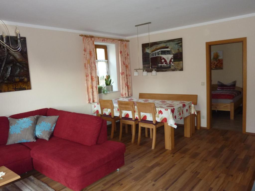 a living room with a red couch and a table at Birkenhof in Leitlitz