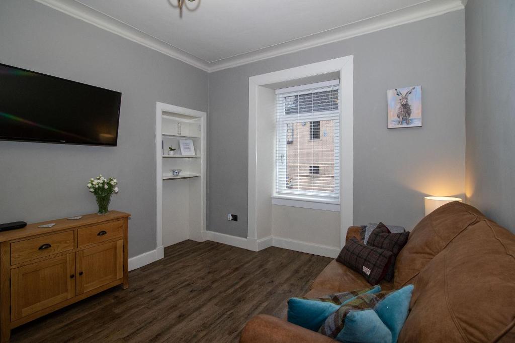 uma sala de estar com um sofá e uma televisão de ecrã plano em Am Meadhan - Comet Apartments em Helensburgh