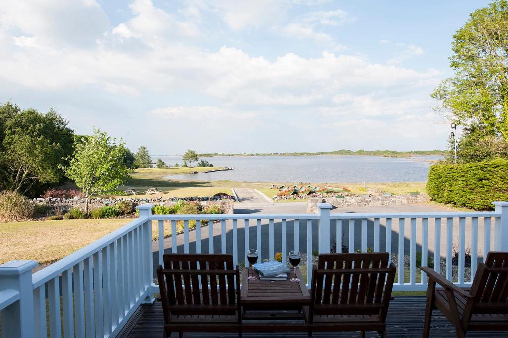 een veranda met 2 stoelen en een tafel met uitzicht op het water bij The Waterfront House Country Home in Oughterard