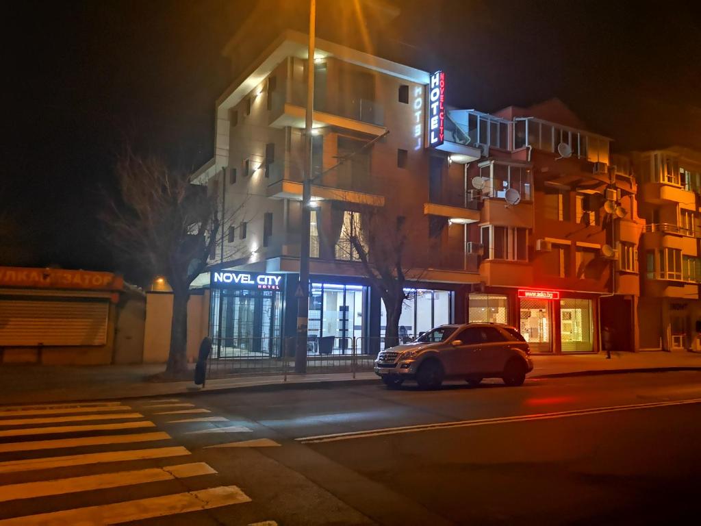 une voiture garée devant un bâtiment la nuit dans l'établissement Family Hotel Novel City, à Bourgas