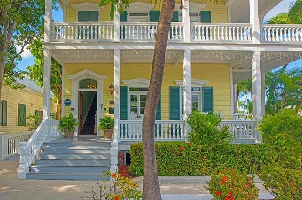 una casa gialla con portico bianco e scale di La Pensione Inn - Adult Exclusive a Key West