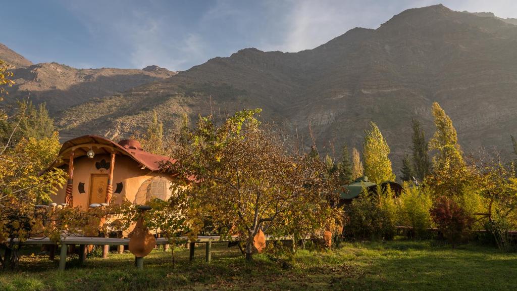 a house in a field with mountains in the background at Cascada Lodge Cajon del Maipo in San José de Maipo