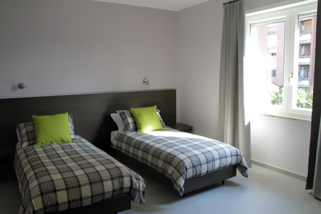 フロジノーネにあるEasyRoom Frosinone - Casello Autostradaleのベッドルーム1室(緑の枕と窓付きのベッド2台付)