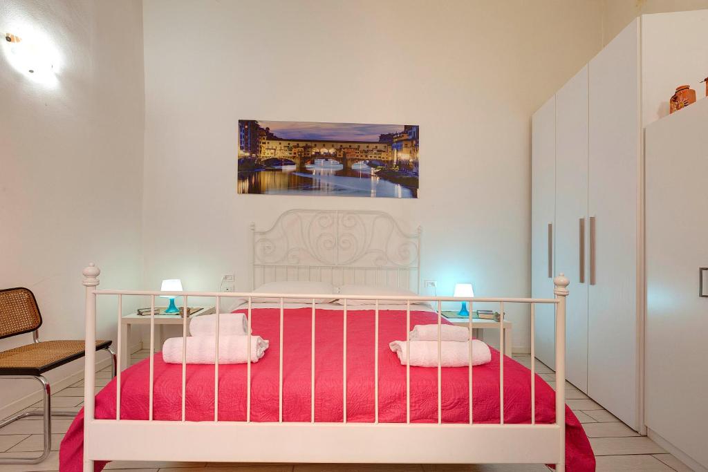 una camera con un letto bianco e lenzuola rosa di Appuntamento a Ponte Vecchio a Firenze