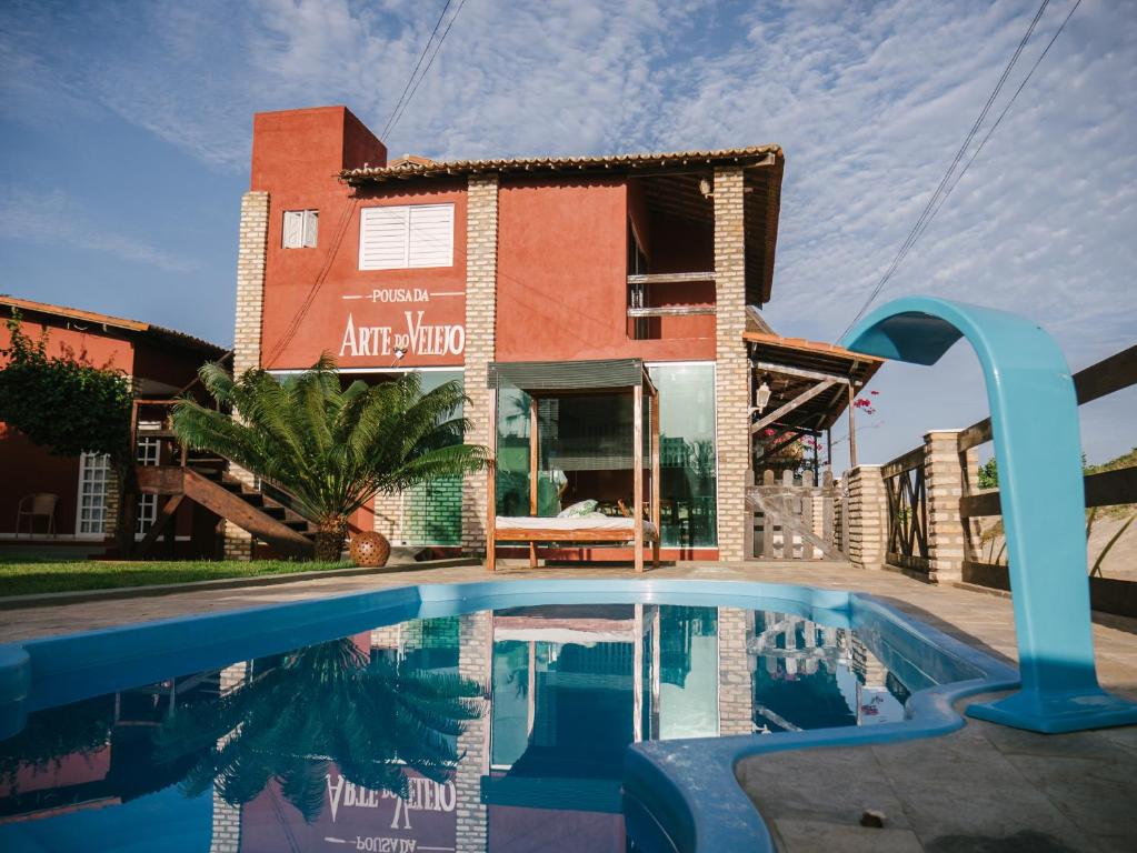 a house with a swimming pool in front of a building at Pousada Arte do Velejo in São Miguel do Gostoso