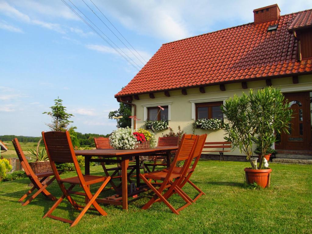 a wooden table and chairs in front of a house at Komblówka in Marcinowa Wola