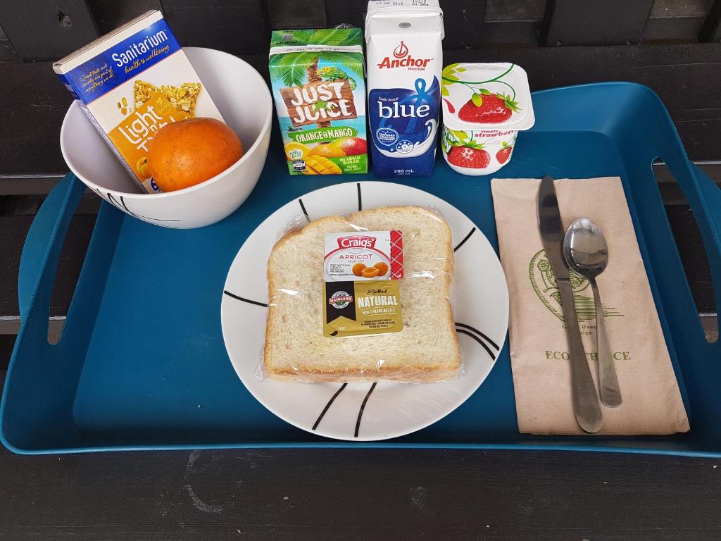 una bandeja azul con un plato con un sándwich y un tazón de comida en Beachcomber Lodge & Backpacker, en Kaitaia