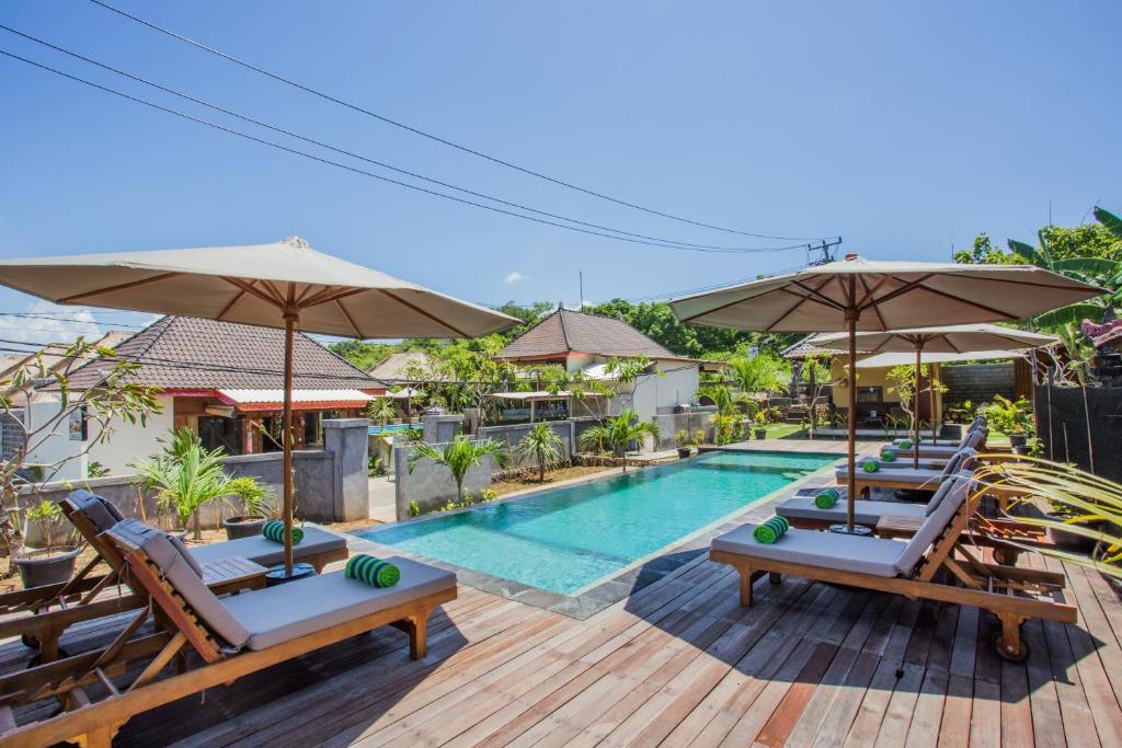 a pool at a resort with lounge chairs and umbrellas at Samanta Huts in Nusa Lembongan