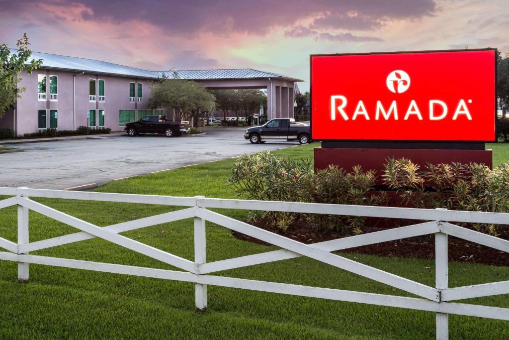 un panneau indiquant un complexe de rammada en face d'un bâtiment dans l'établissement Ramada by Wyndham Luling, à Luling