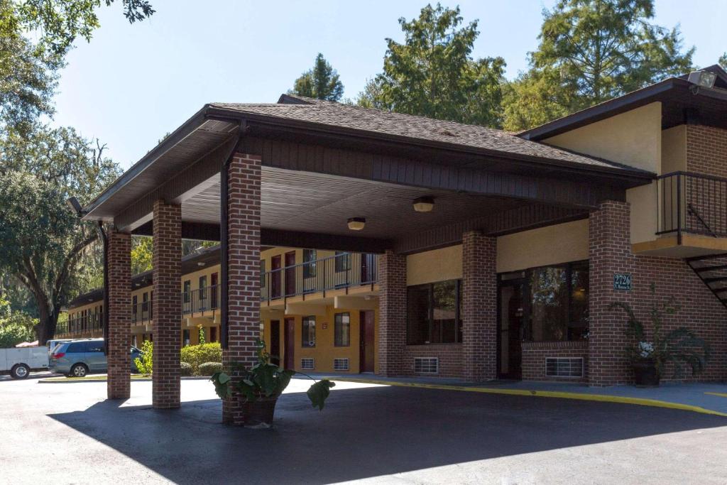 un grande edificio in mattoni con portico in un parcheggio di Howard Johnson by Wyndham Tallahassee a Tallahassee