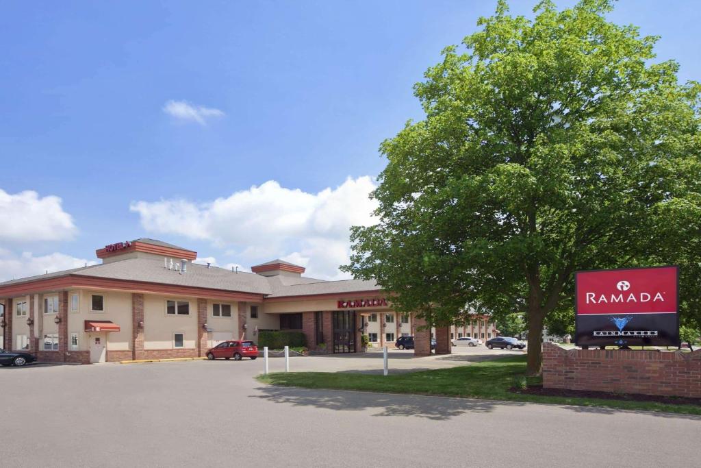 un hotel con un cartel frente a un edificio en Ramada by Wyndham Saginaw Hotel & Suites, en Saginaw