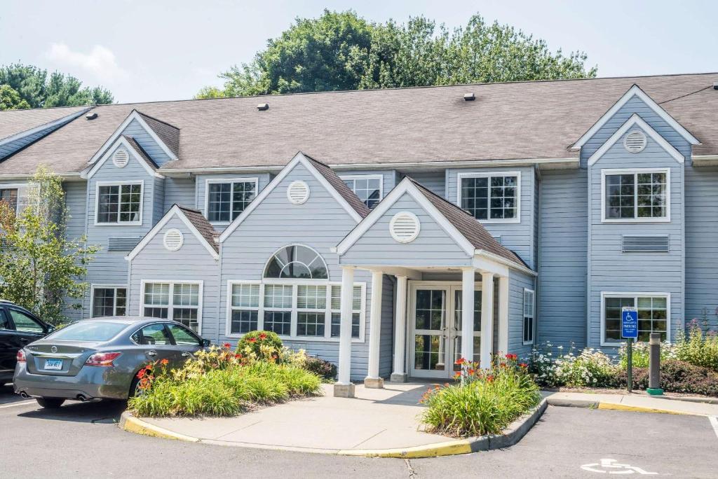 una casa azul con un coche aparcado delante de ella en Microtel Inn & Suites by Wyndham Bethel/Danbury en Bethel