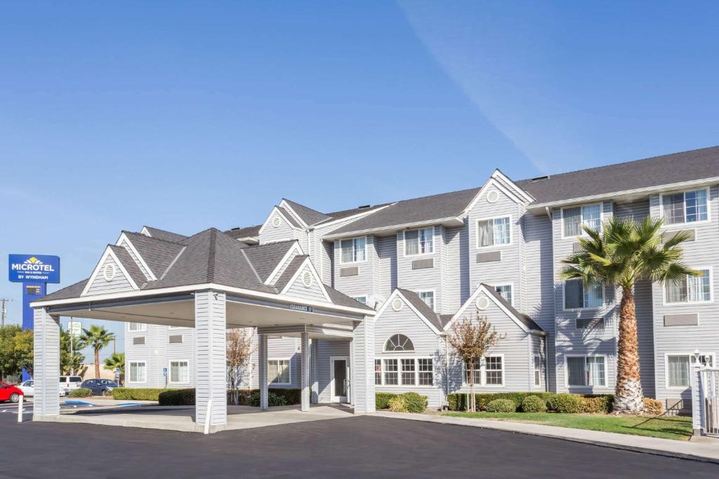 a large white building with a palm tree at Microtel Inn & Suites Modesto in Ceres