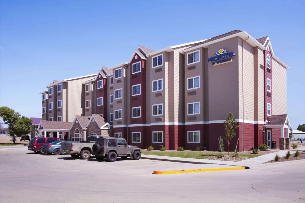 a large building with cars parked in a parking lot at Microtel Inn & Suites in Sidney