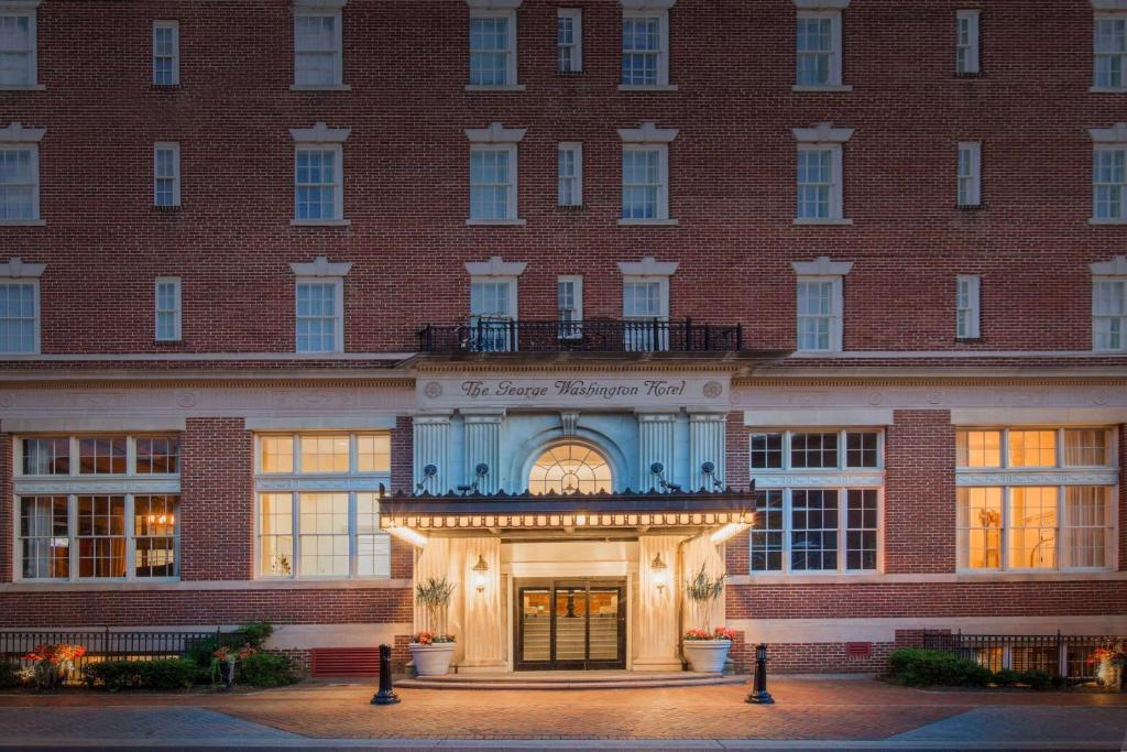 a large red brick building with the entrance to a hotel at The George Washington - A Wyndham Grand Hotel in Winchester