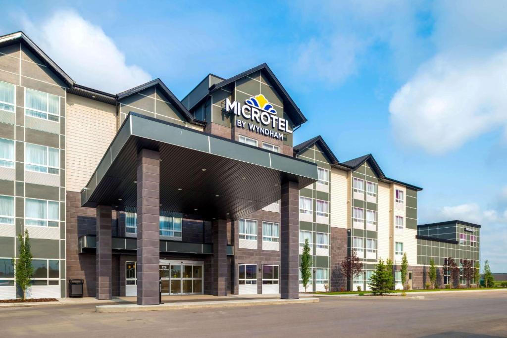 a hotel building with a sign on the front of it at Microtel Inn & Suites by Wyndham Red Deer in Red Deer