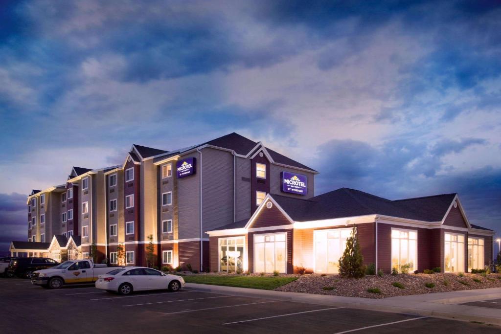 a hotel with cars parked in a parking lot at Microtel Inn & Suites by Wyndham Vernal/Naples in Vernal