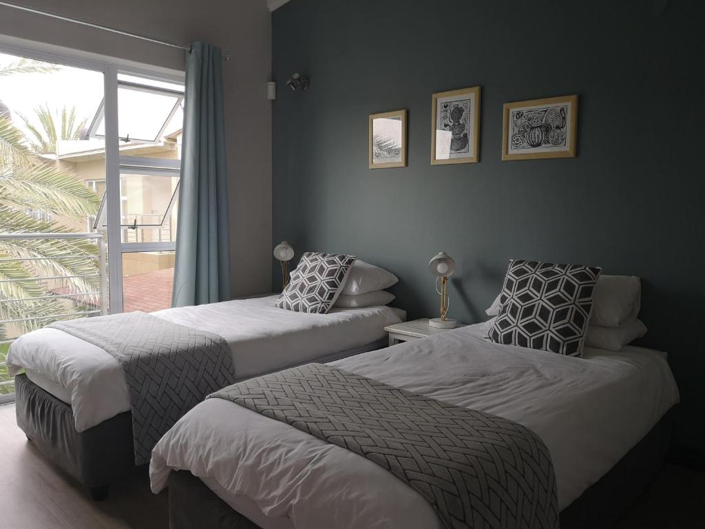 two beds in a room with a window at The Waterfront Cottage F12 in Swakopmund