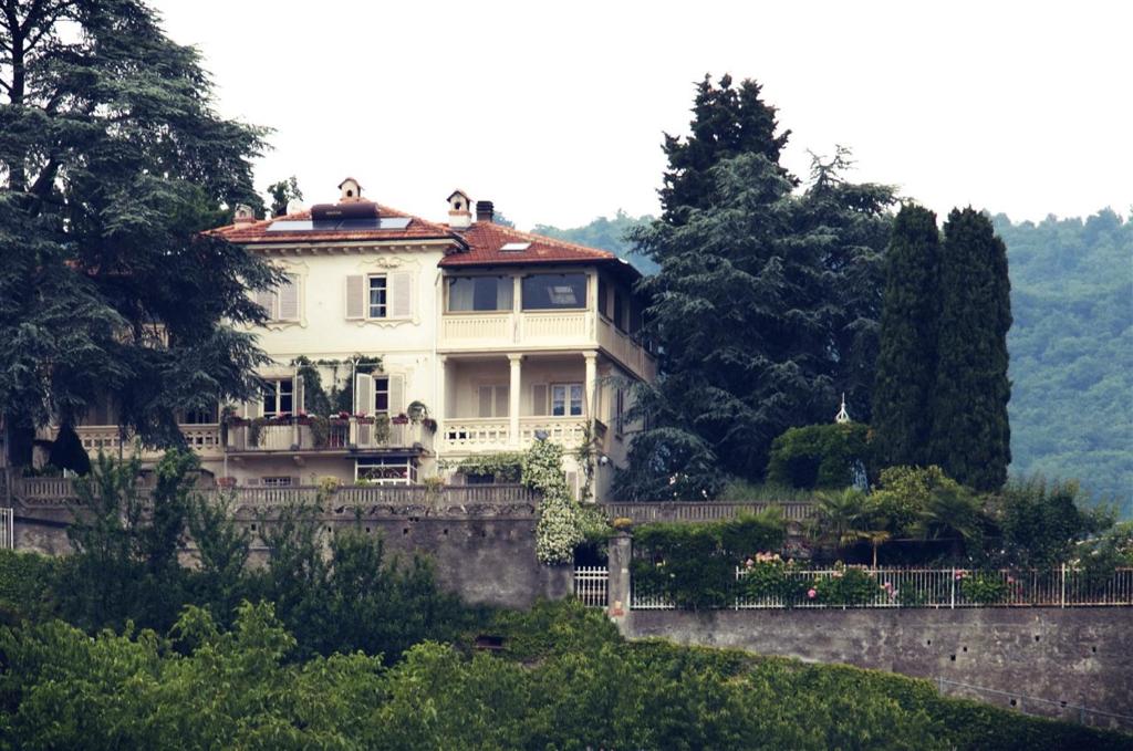 ein großes weißes Haus auf einem Hügel mit Bäumen in der Unterkunft Novecento B&B in Bollengo
