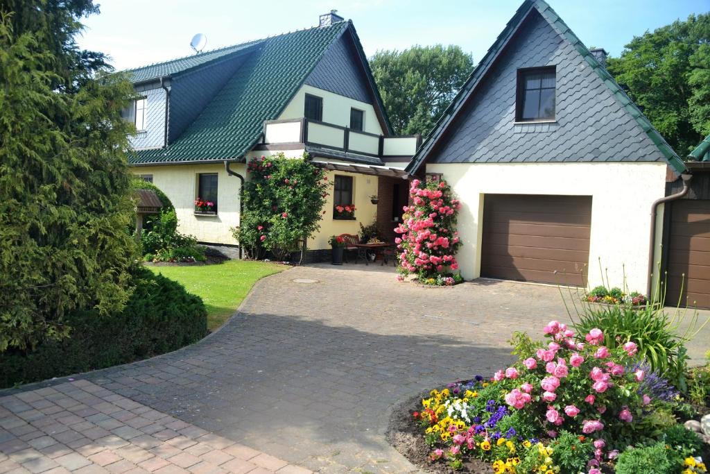 a white house with a garage and some flowers at Ferienwohnung 1 bei Familie Saupe in Schaprode