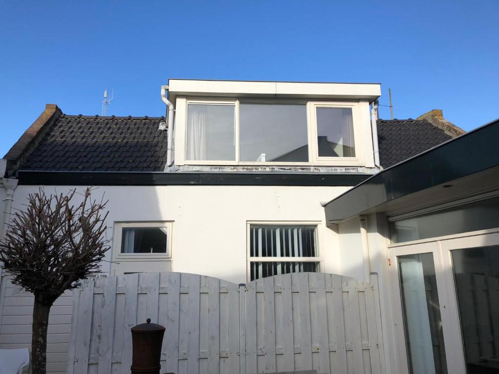 a white house with a white fence and a window at BenSan Beach House Zandvoort with Private Parking in Zandvoort