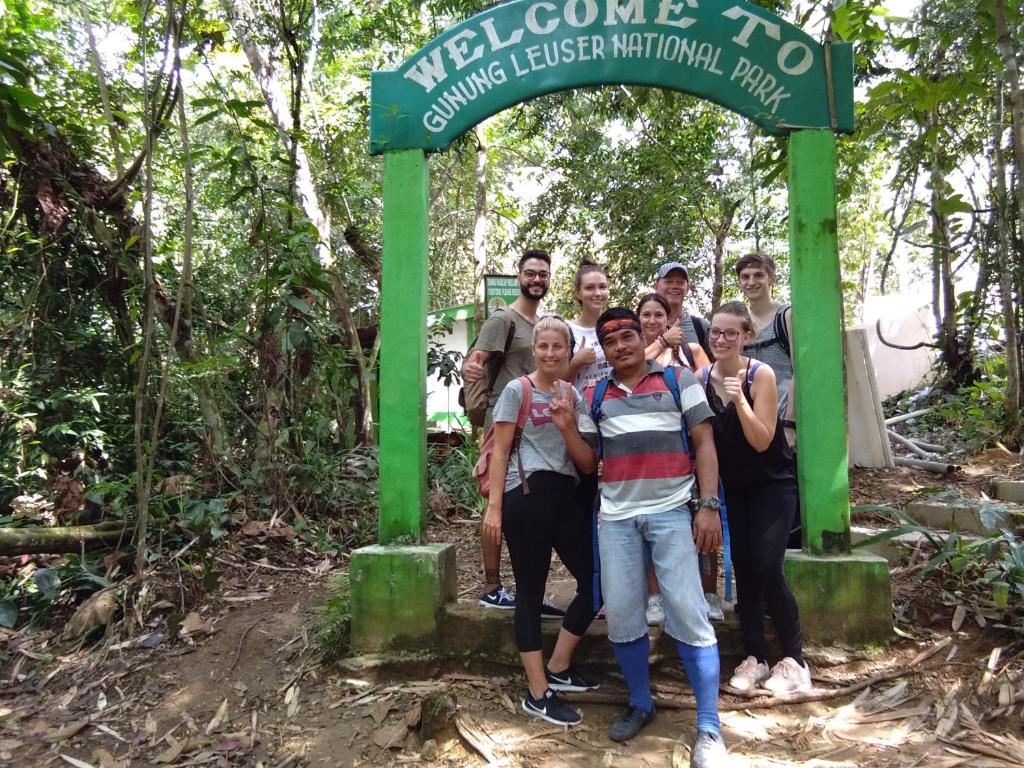 a group of people standing under a sign in the forest at Jungle Trekking & Jungle Tour only stay here if you are and you must booking jungle trekking with us in Bukit Lawang