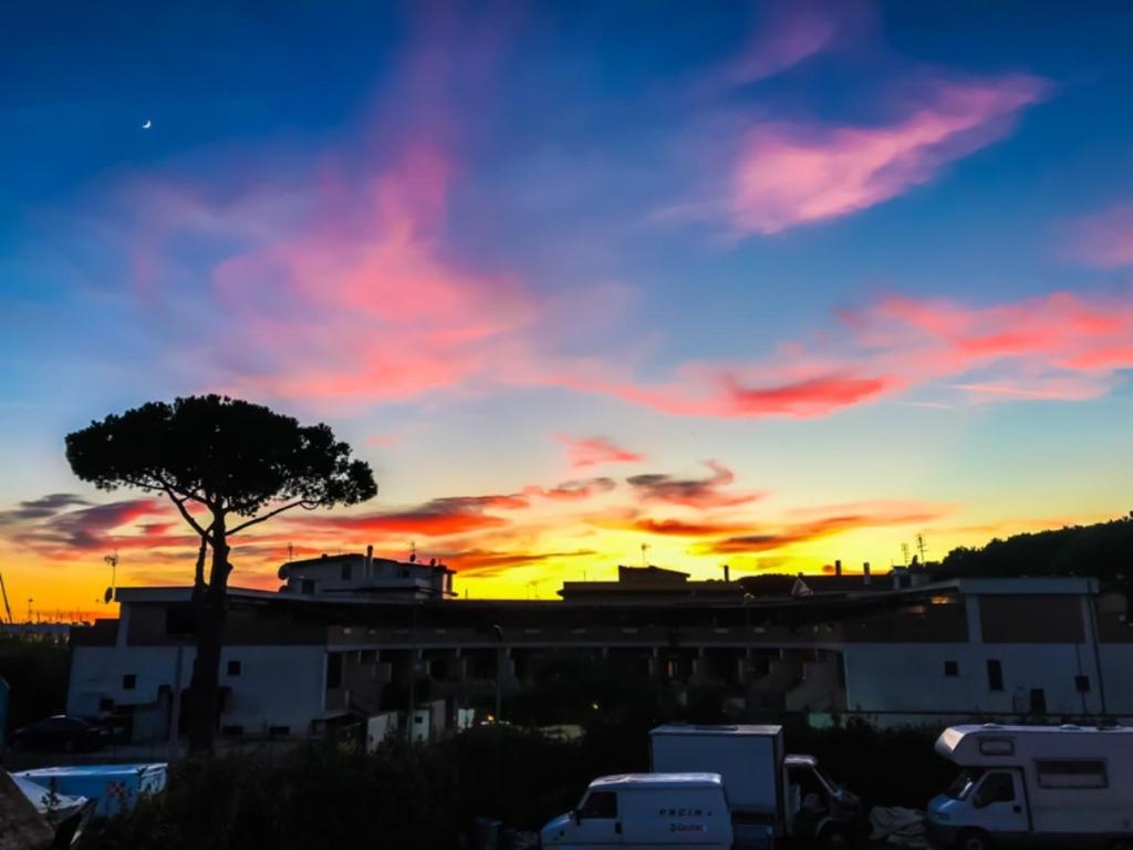 a sunset with a tree in a parking lot at Isola Verde Guest House in Fiumicino