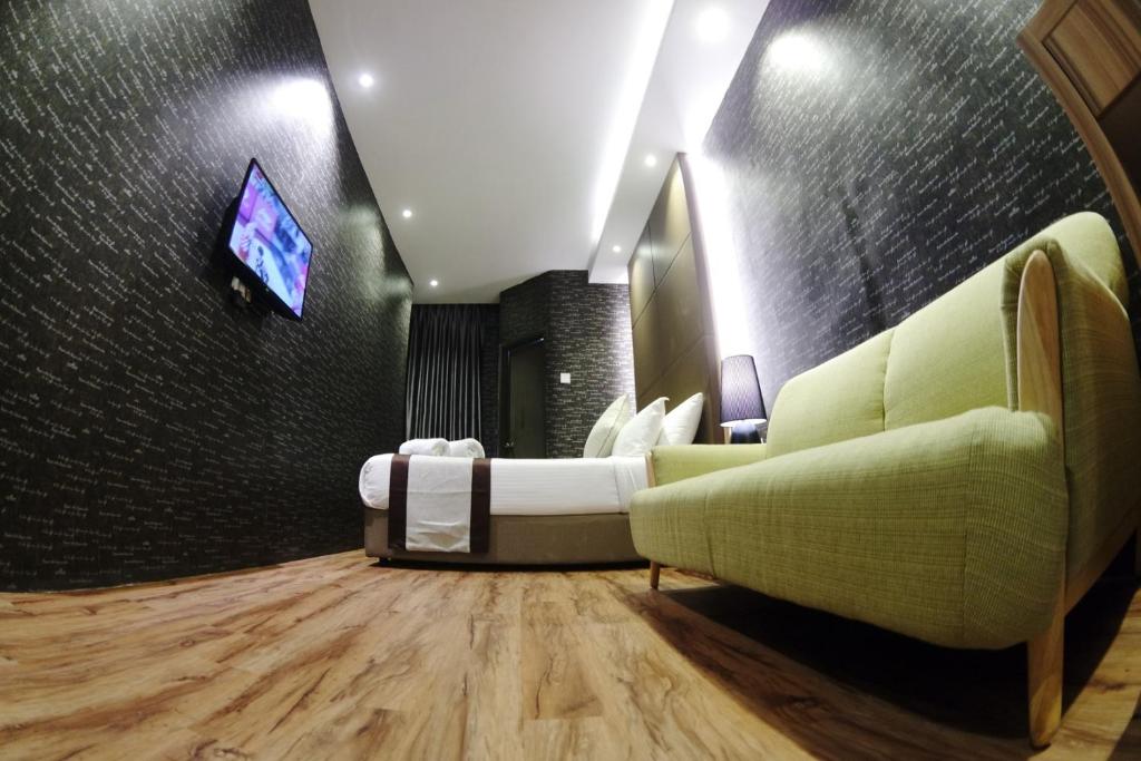 salon z kanapą i telewizorem na ścianie w obiekcie Here Hotel w mieście Skudai