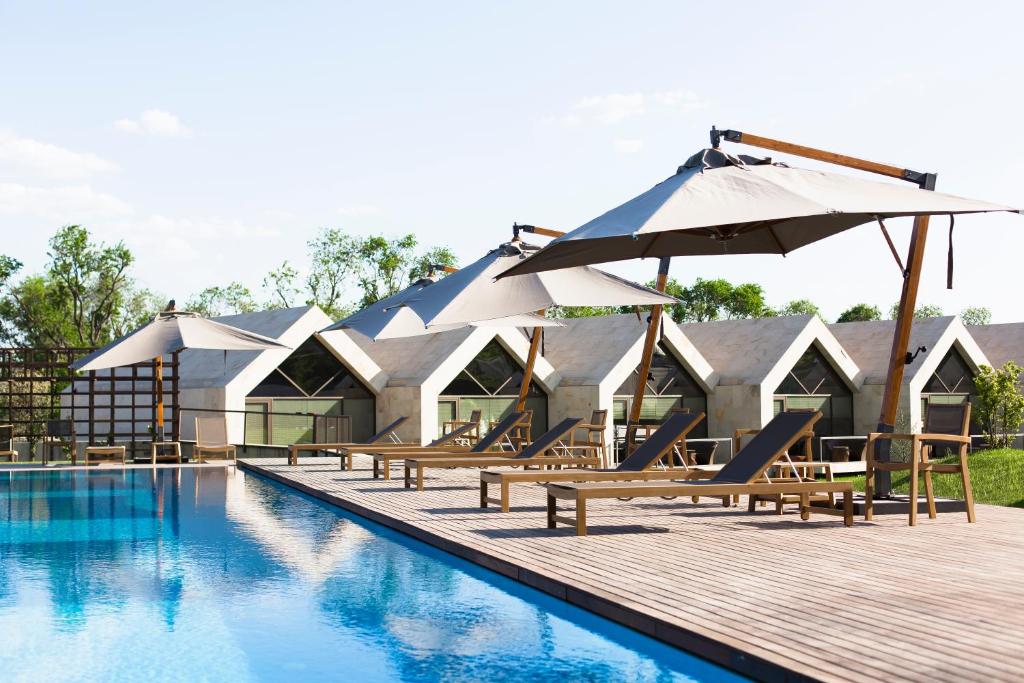 a swimming pool with chairs and umbrellas next to a resort at Castel Mimi Wine Resort in Bulboaca