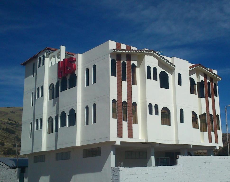 a white building with a red sign on it at Hostal Campestre Casa Blanca in Chucuito