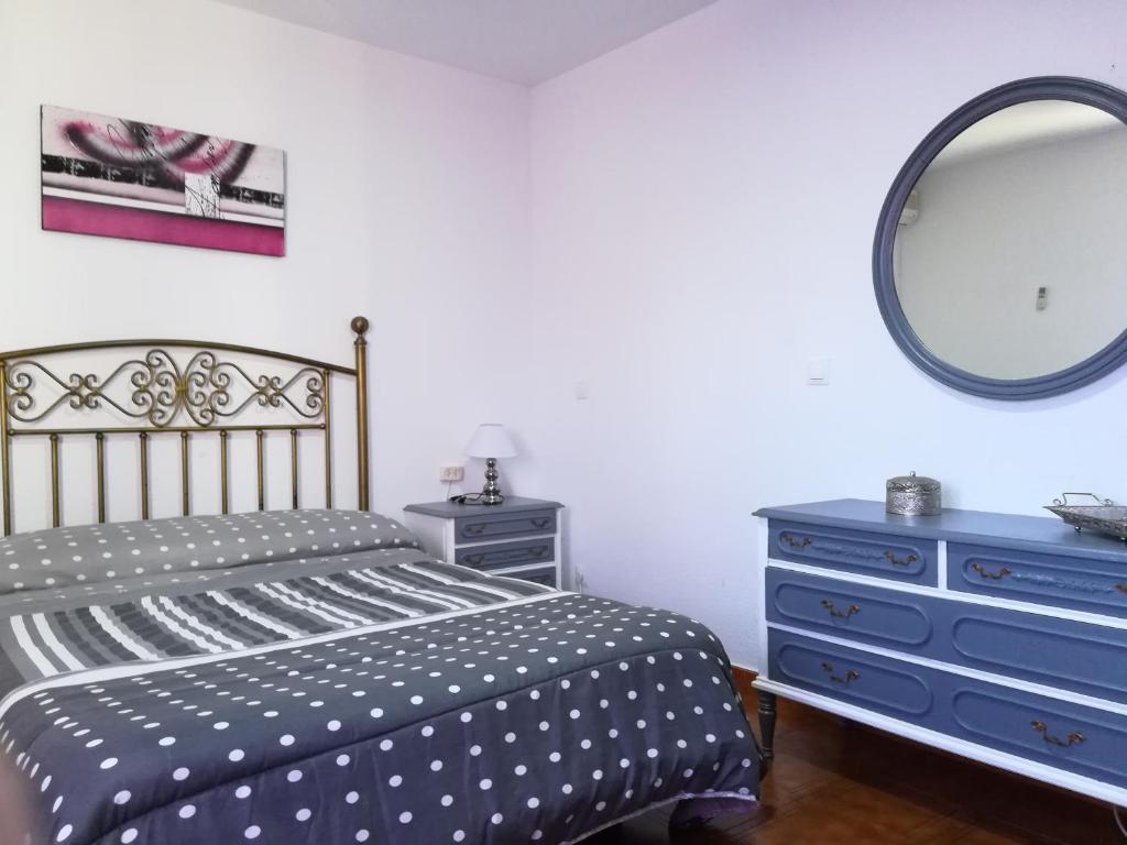 a bedroom with a bed and a dresser and a mirror at Casas los Rosales in Guadix