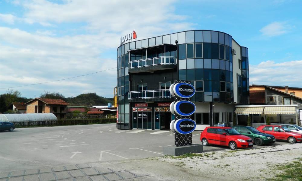 a parking lot with cars parked in front of a building at Hollywood Motel in Podlugovi