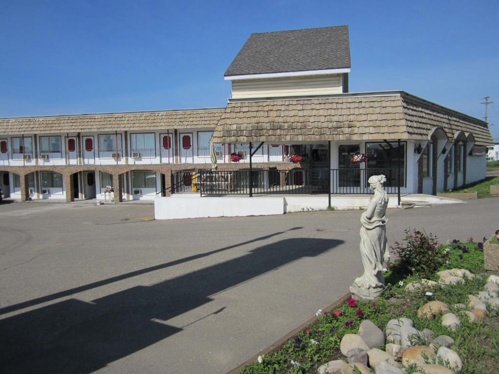 une statue d'une femme devant un bâtiment dans l'établissement Peace Villa Motel, à Dawson Creek