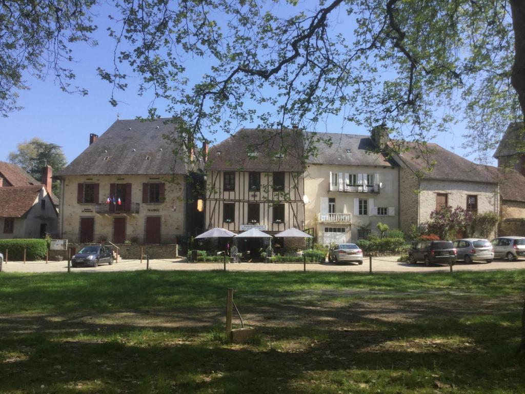 un gran edificio con coches estacionados frente a él en Auberge Henri IV, en Ségur-le-Château