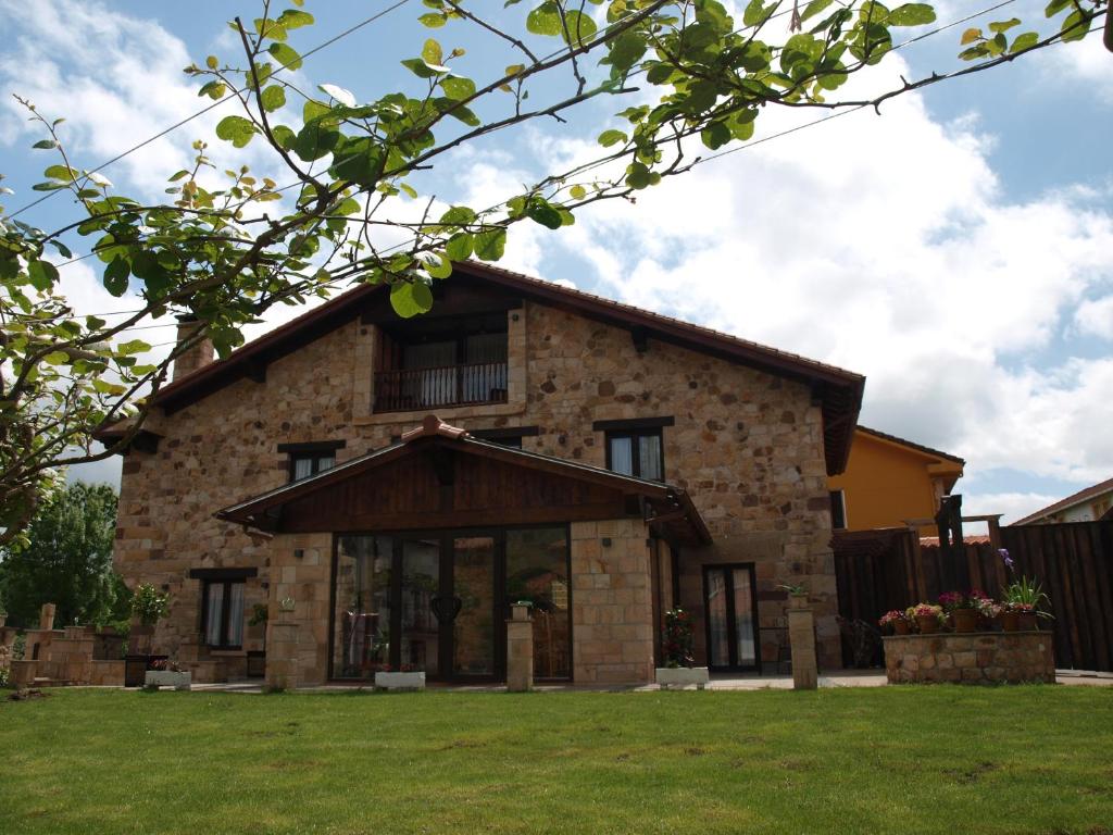 a large stone house with a green yard at Posada Venero in Cabárceno