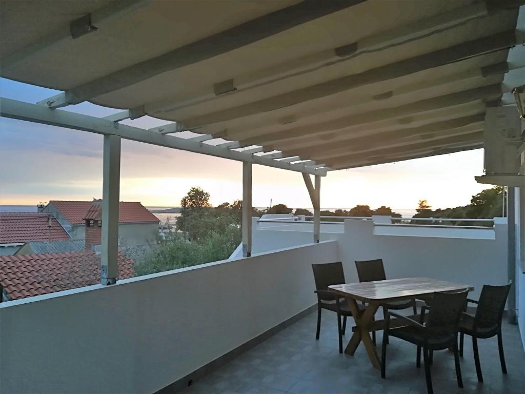 eine Terrasse mit einem Tisch und Stühlen auf dem Balkon in der Unterkunft Apartman Rosanda 1 in Premuda