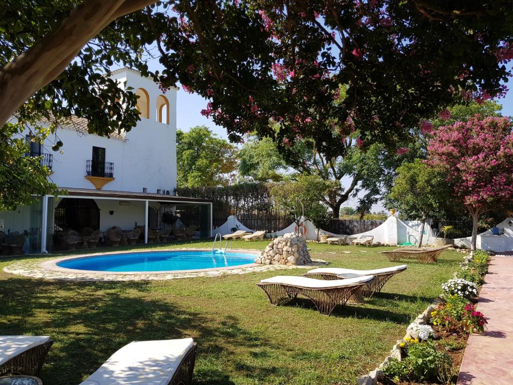 a backyard with a swimming pool and a house at Hacienda el Santiscal in Arcos de la Frontera