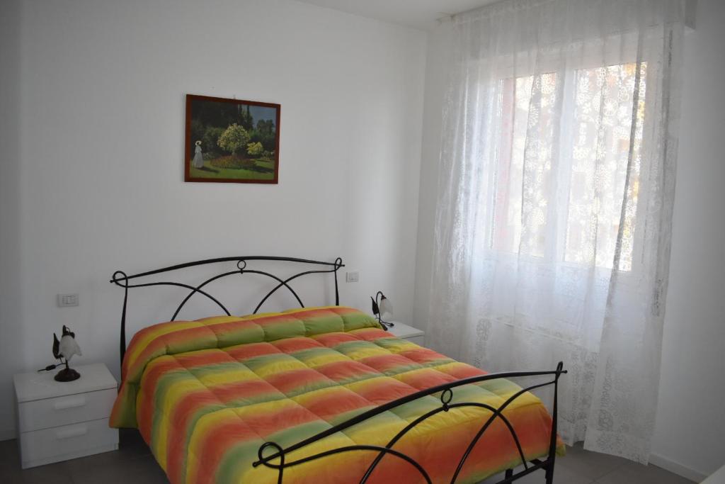 - une chambre avec un lit doté d'une couverture colorée et d'une fenêtre dans l'établissement Residence Borsellino 41, à Garbagnate Milanese