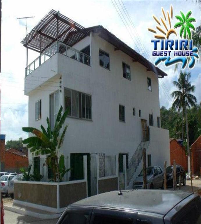 a large white house with a car parked in front of it at Pousada Tiriri Guesthouse in Barra do Camaragibe