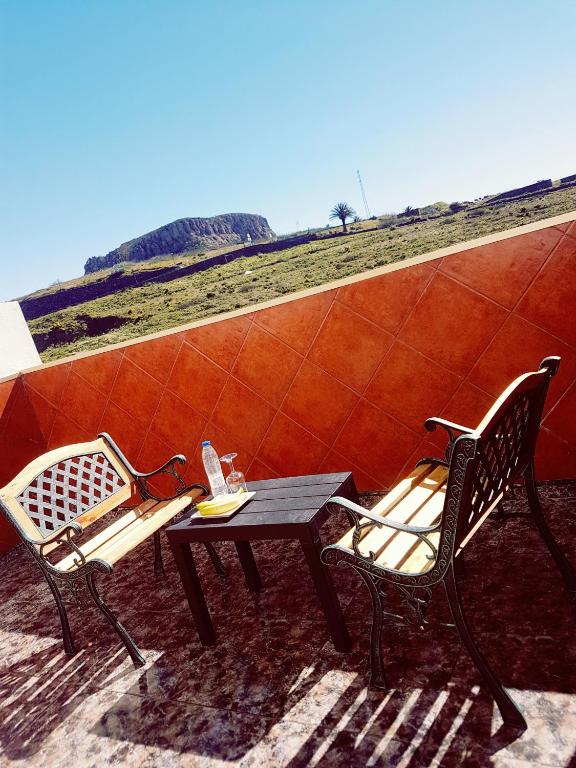 two chairs and a table on a patio with a view of a field at Hotel Sonia Chipude in El Cercado
