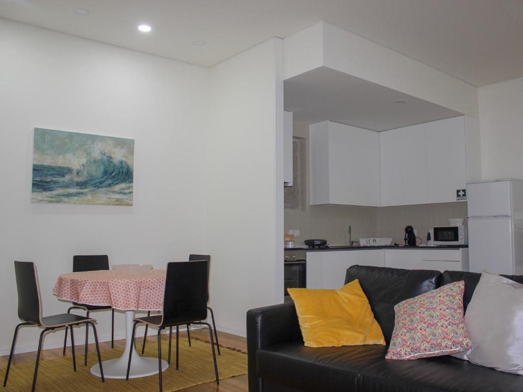 a living room with a couch and a table with chairs at Banho de Mar in Póvoa de Varzim