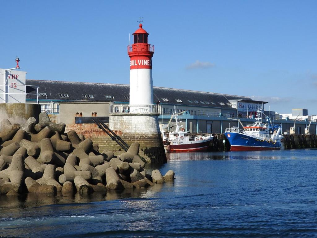 ein Leuchtturm in einem Hafen mit Booten im Wasser in der Unterkunft Au bout du Port in Le Guilvinec