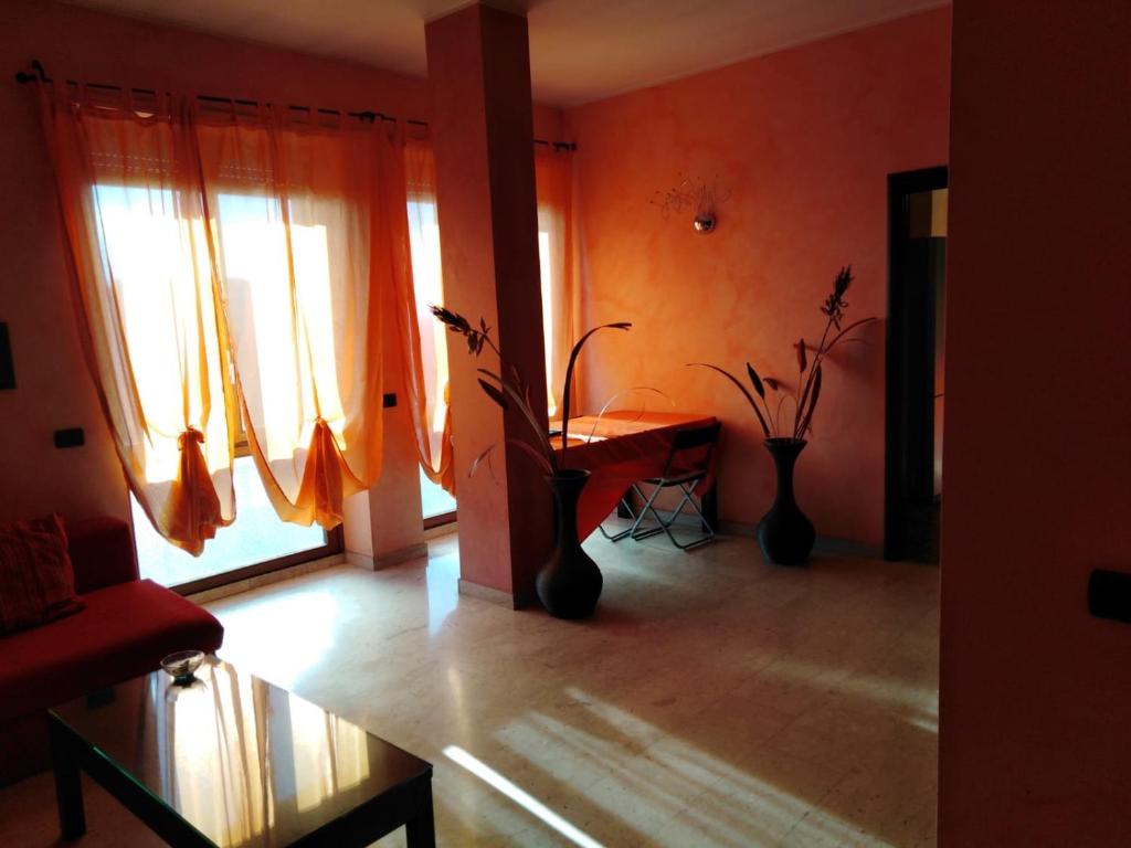 - un salon avec des rideaux orange et une table ornée de plantes dans l'établissement Residence Taverna, à Plaisance