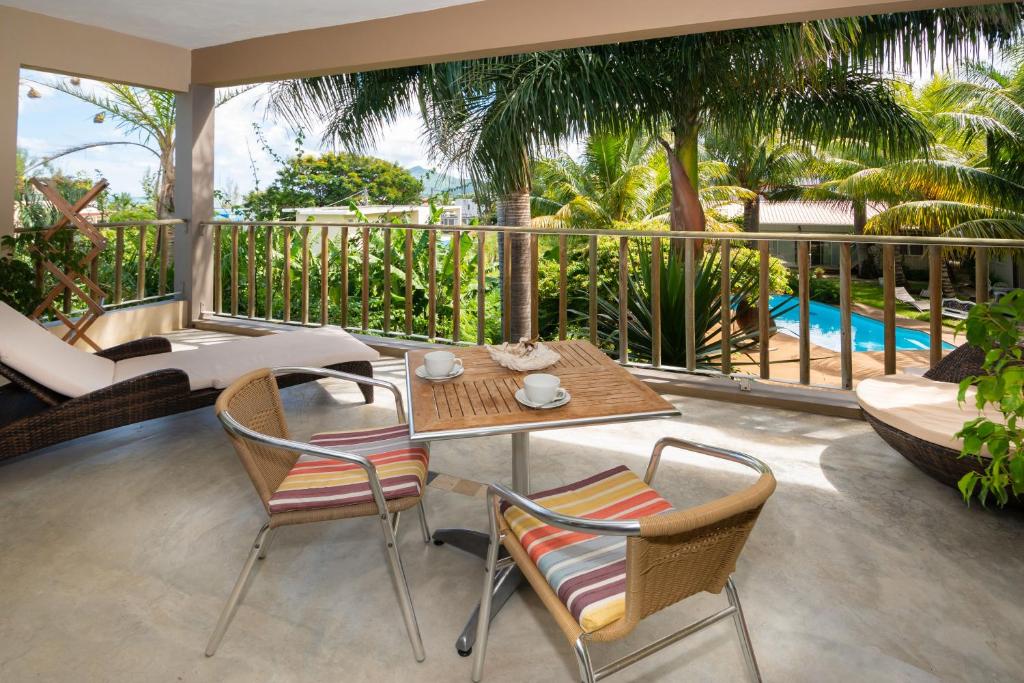 a patio with a table and chairs on a balcony at Rusty Pelican Heavenly Apt in La Gaulette