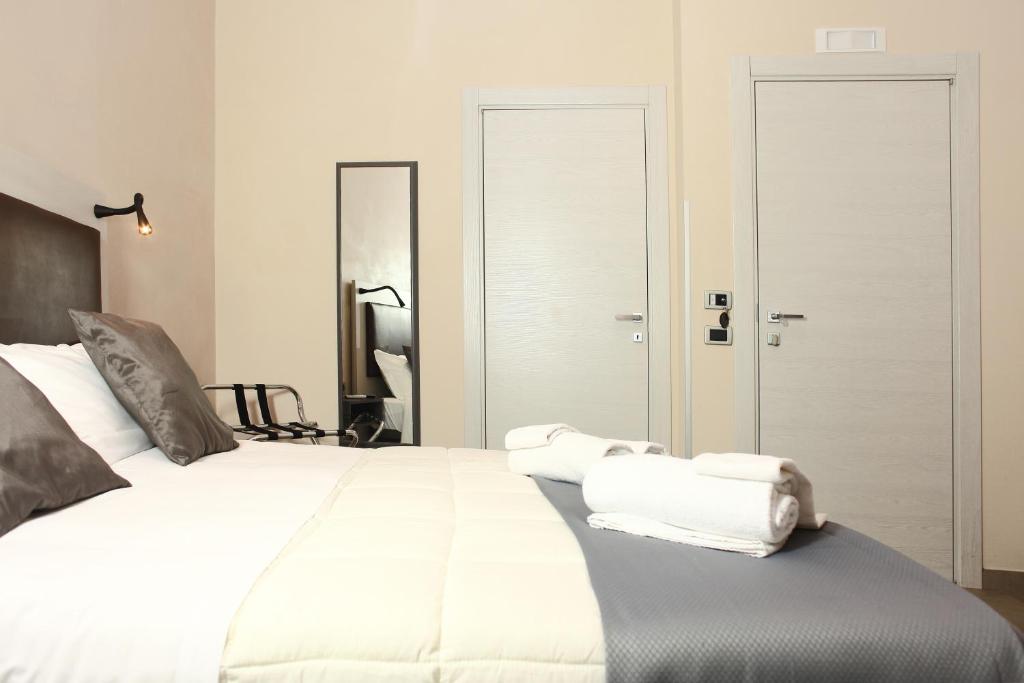una camera da letto con un grande letto bianco con asciugamani di Albergo Maccotta a Trapani
