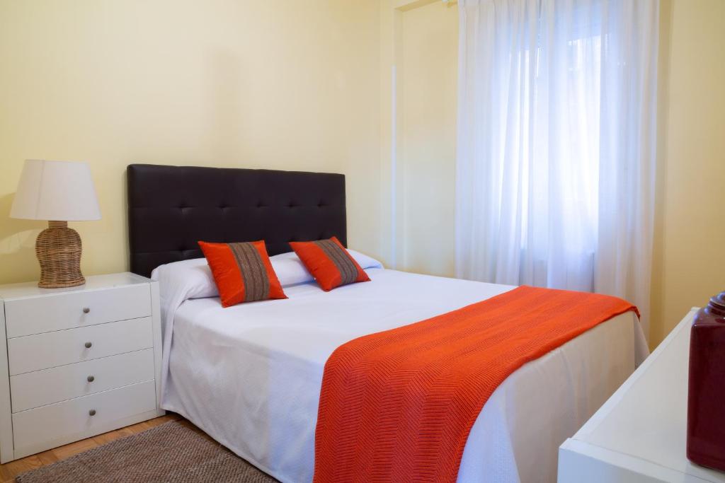 Un dormitorio con una cama con una manta naranja. en Apartamentos Duque Martinez Izquierdo., en Madrid